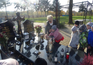 Dziewczynka odkłada z pomocą pani Arlety znicz na grób księdza Bogusława Palenickiego oraz księdza Ryszarda Kolibskiego.